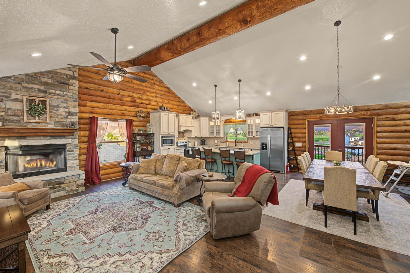 Cozy great room with a lit stone fireplace and log walls at Cliffrose Cabin in Kanab